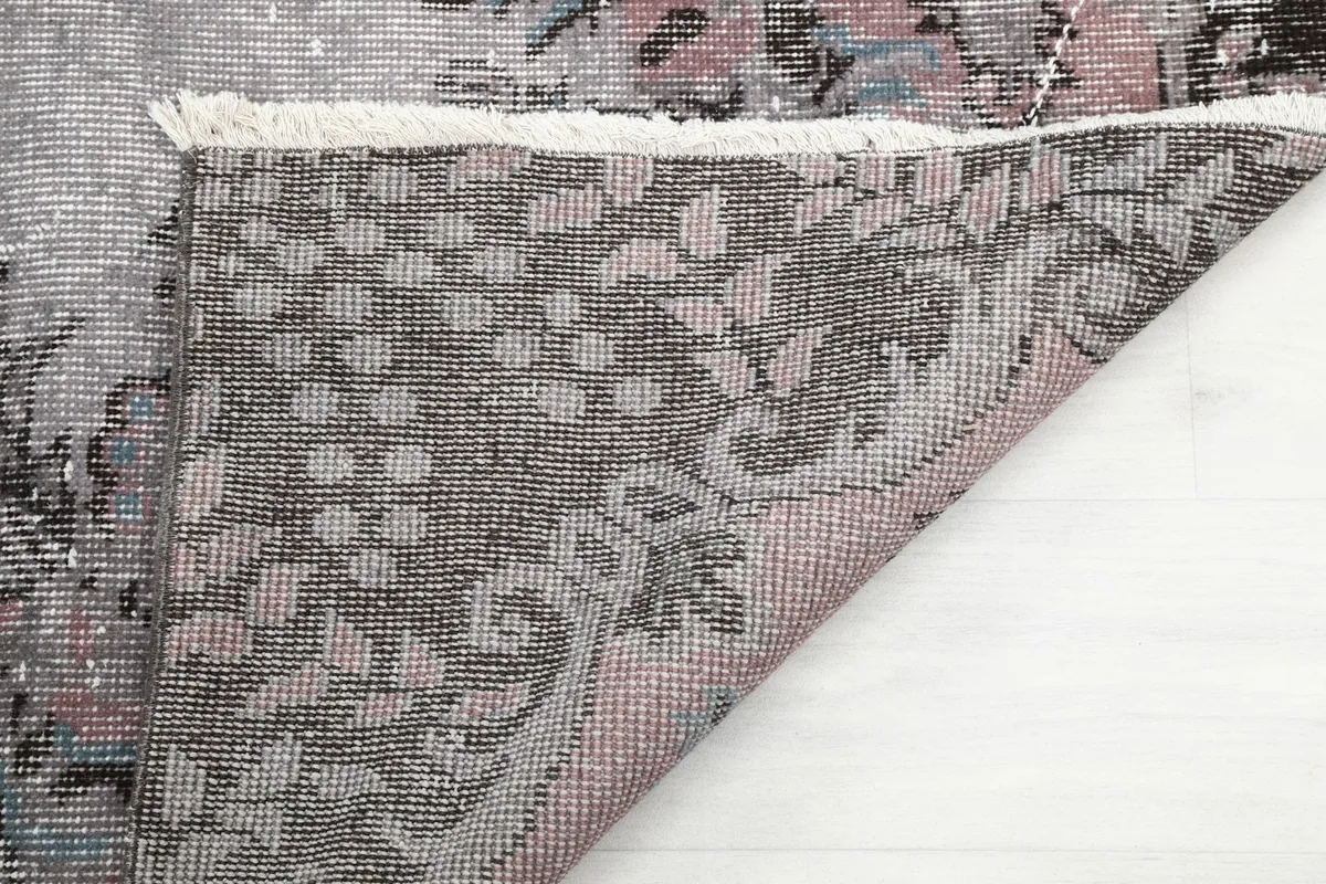 Close-up of the rug's underside, showing the intricate knotting and fringe