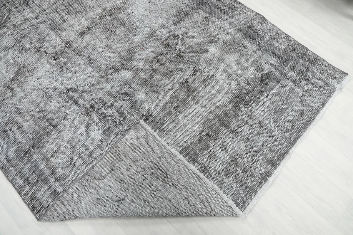 Corner of the Charcoal Faded Abstract Rug folded back, revealing the cotton foundation and hand-knotted construction.
