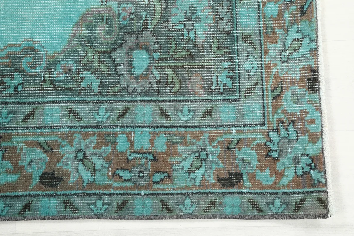 Detailed view of the intricate brown and gray border patterns on the vintage rug