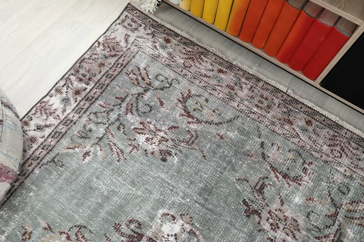 Corner view of the rug, capturing the border design and a glimpse of the worn pile