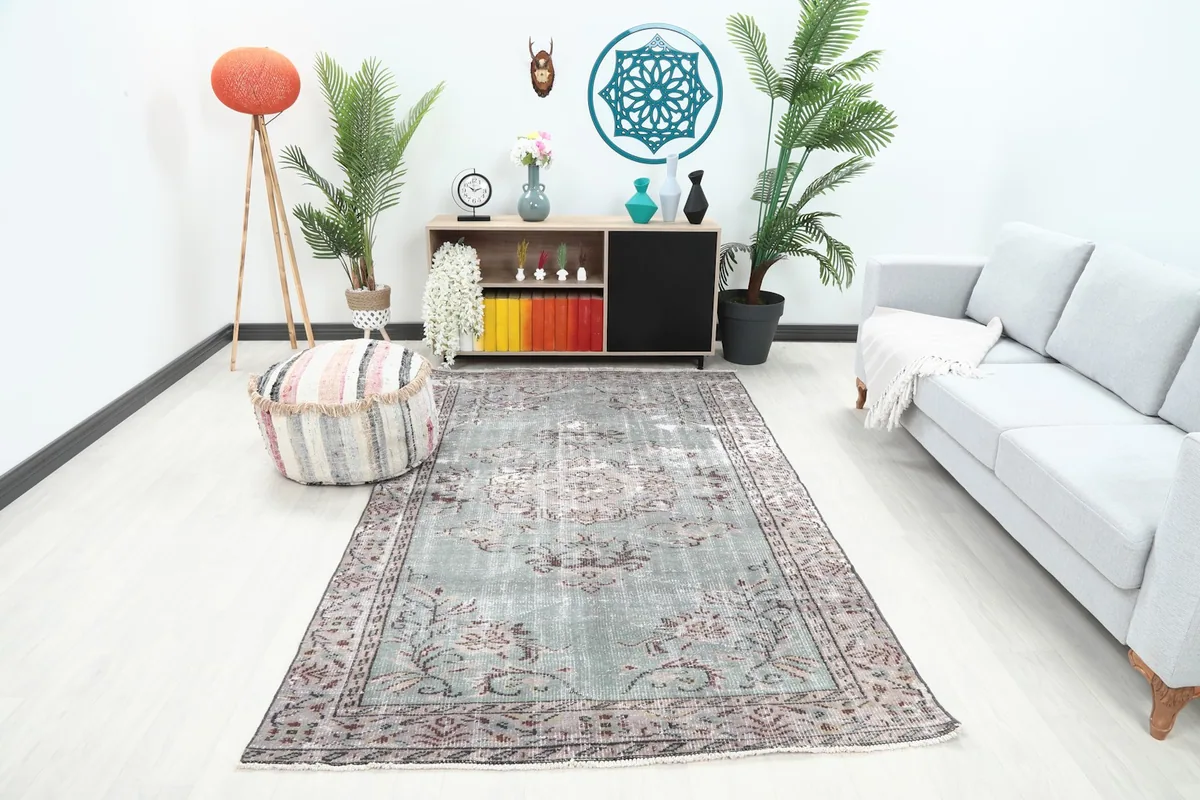 Vintage Anatolian rug displayed in a living room setting with a sofa and plants