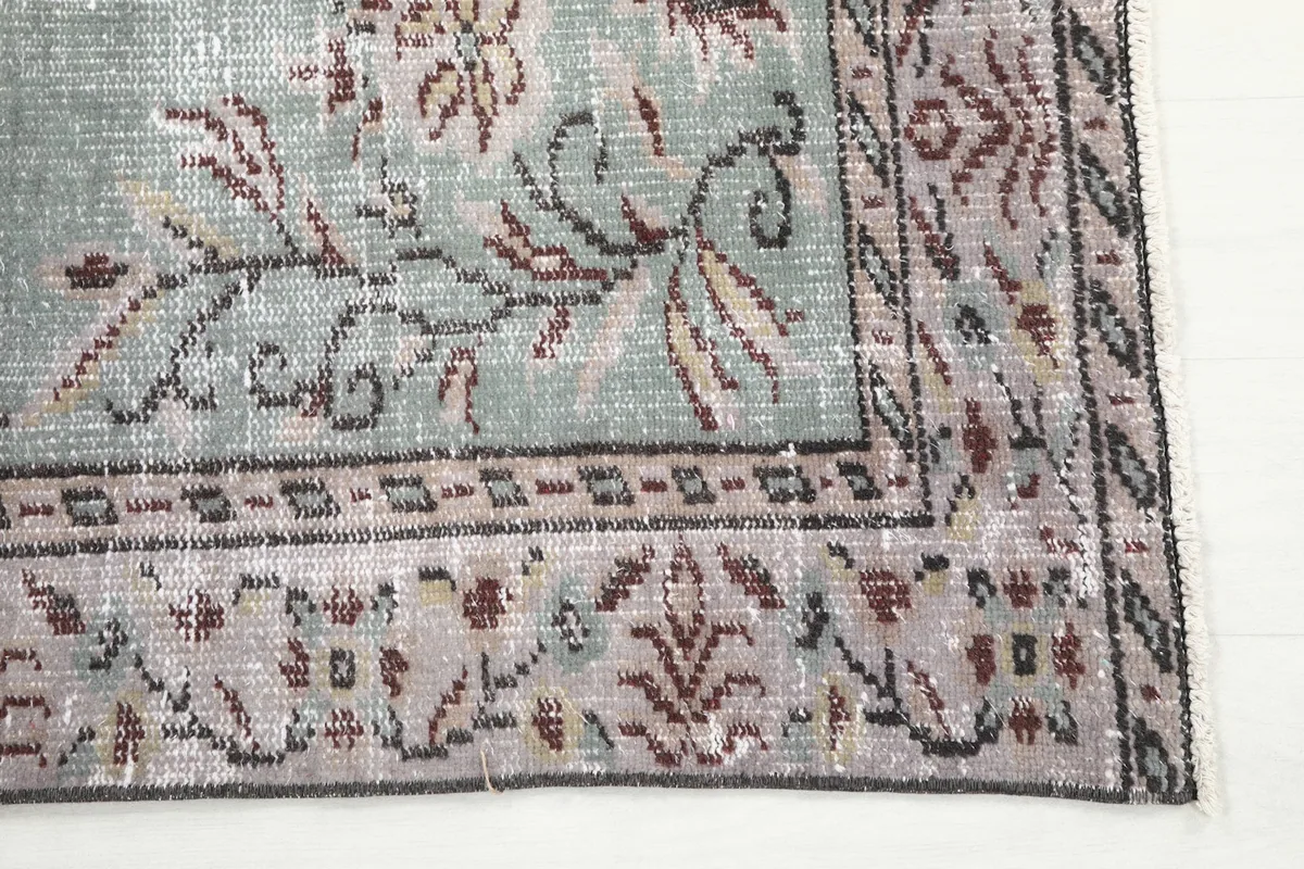 Detailed view of the intricate rose and brown floral motifs within the rug's border