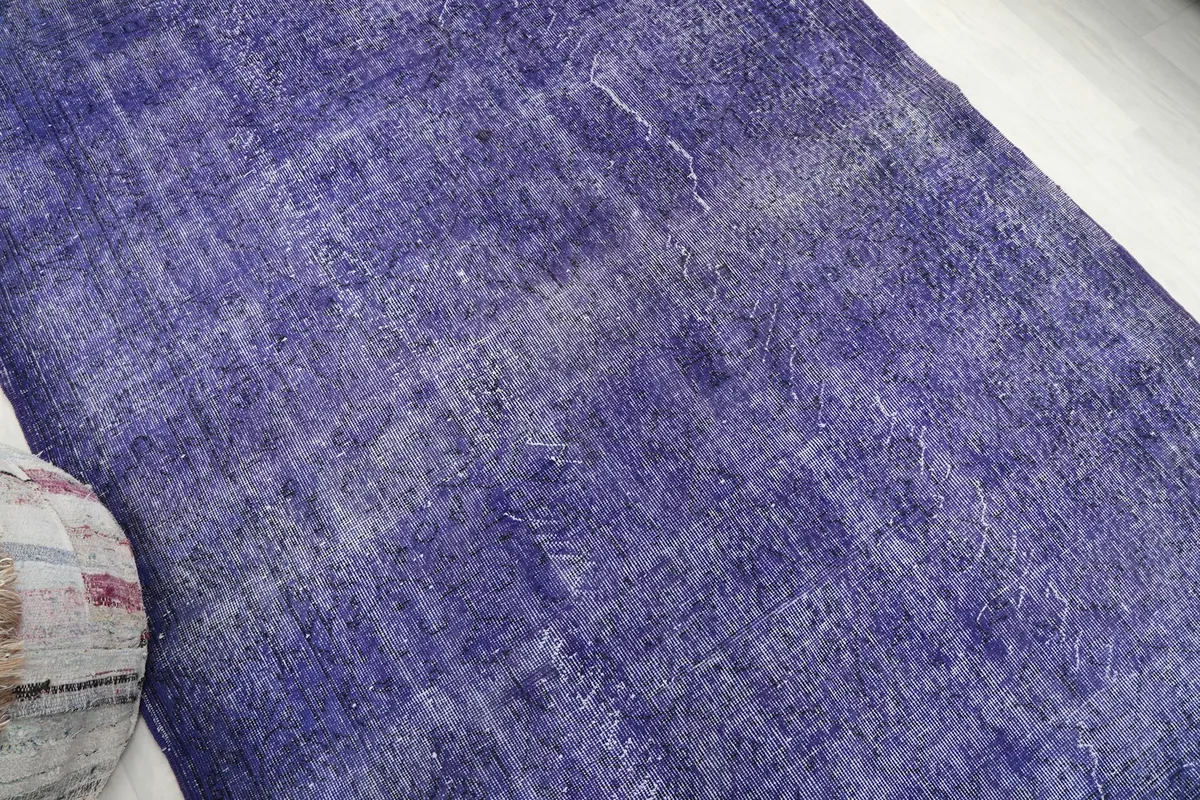 Another angle shot of the rug's surface, emphasizing the worn, vintage character and purple tones.