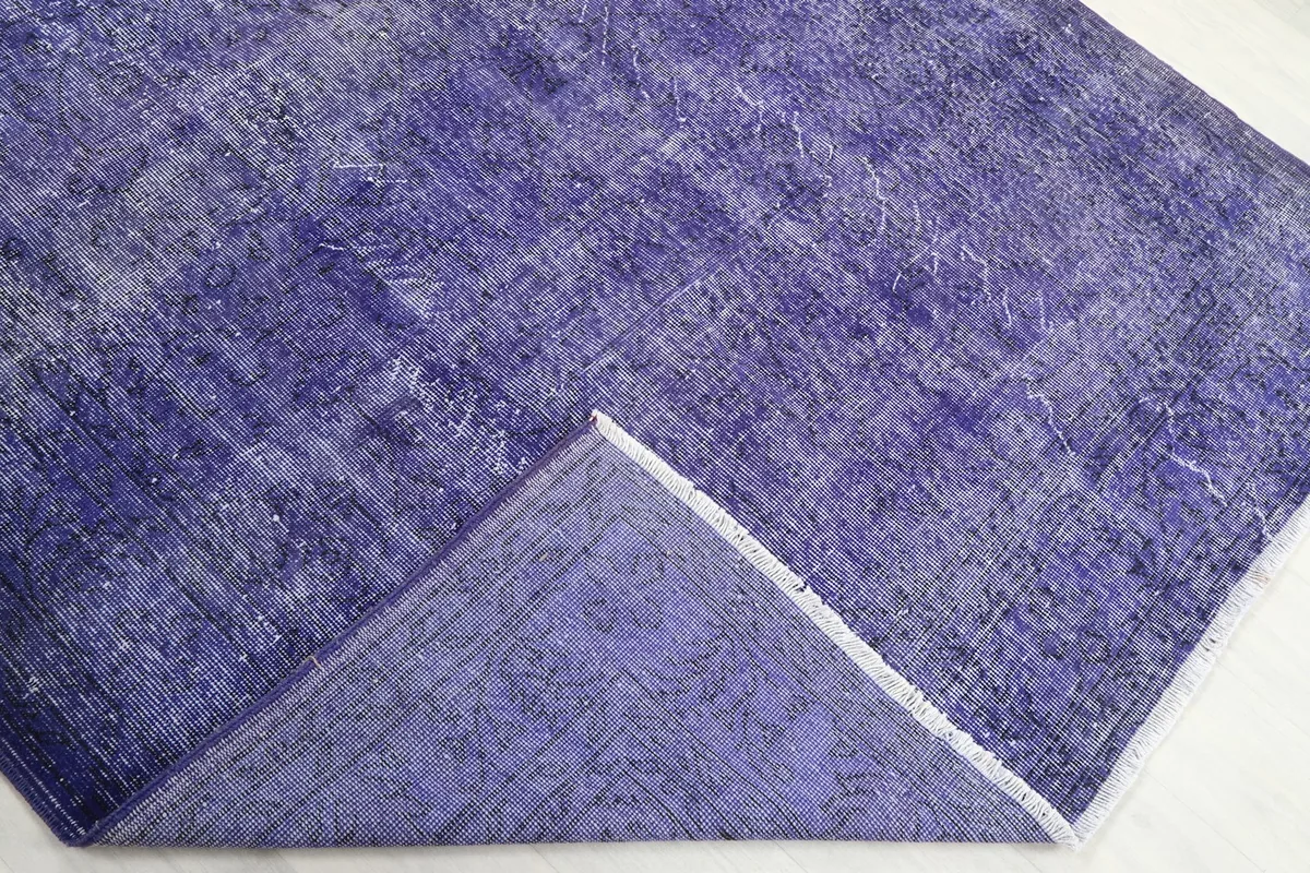 Corner of the rug folded back to reveal the cotton foundation and the hand-knotted construction from the reverse side.