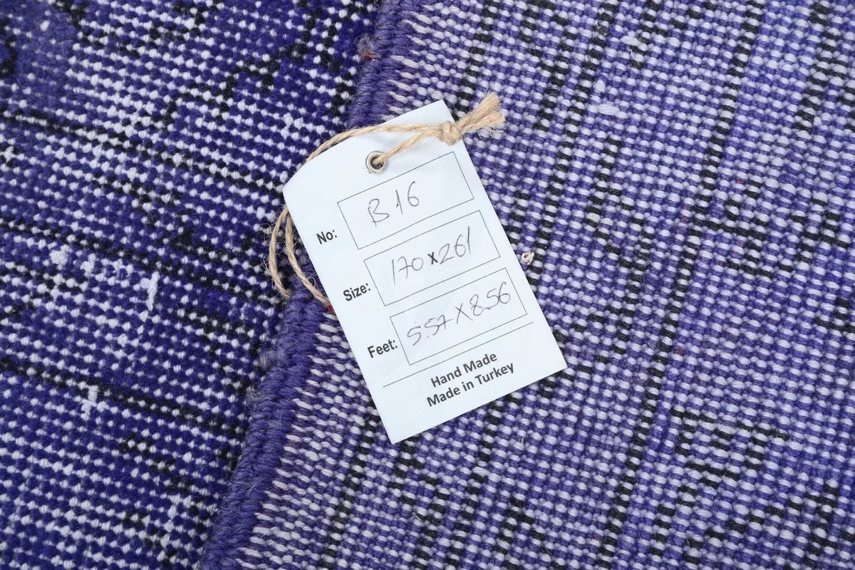 Detail of the rug with a tag displaying its dimensions, 'Hand Made', and 'Made in Turkey'.