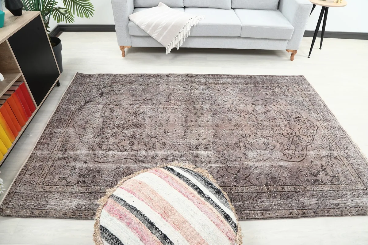 Wide shot of the 5'6" x 8'3" charcoal rug in a room setting, showing its scale with a sofa and ottoman.
