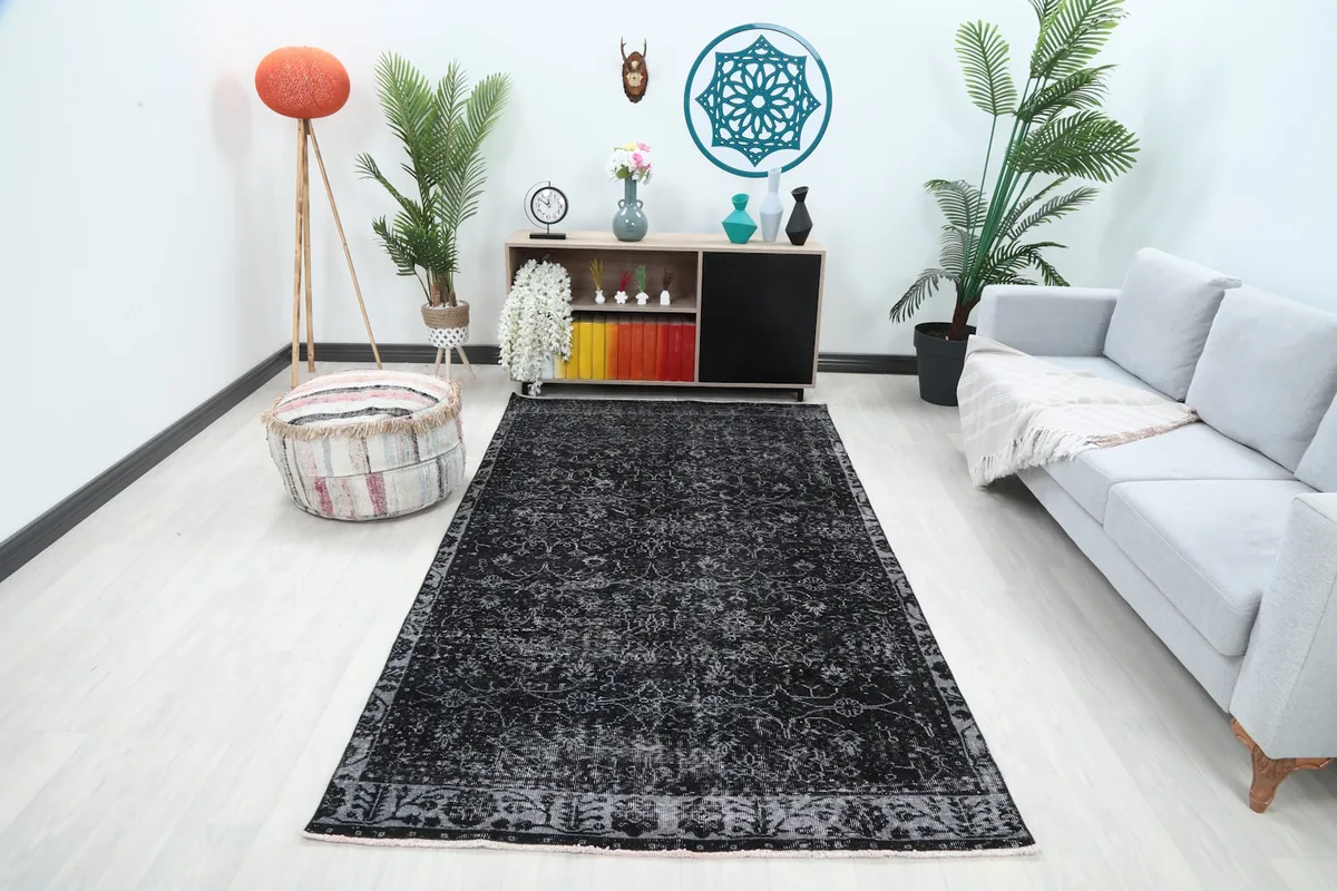 Vintage black and gray rug placed in a modern living room setting with a sofa and plants
