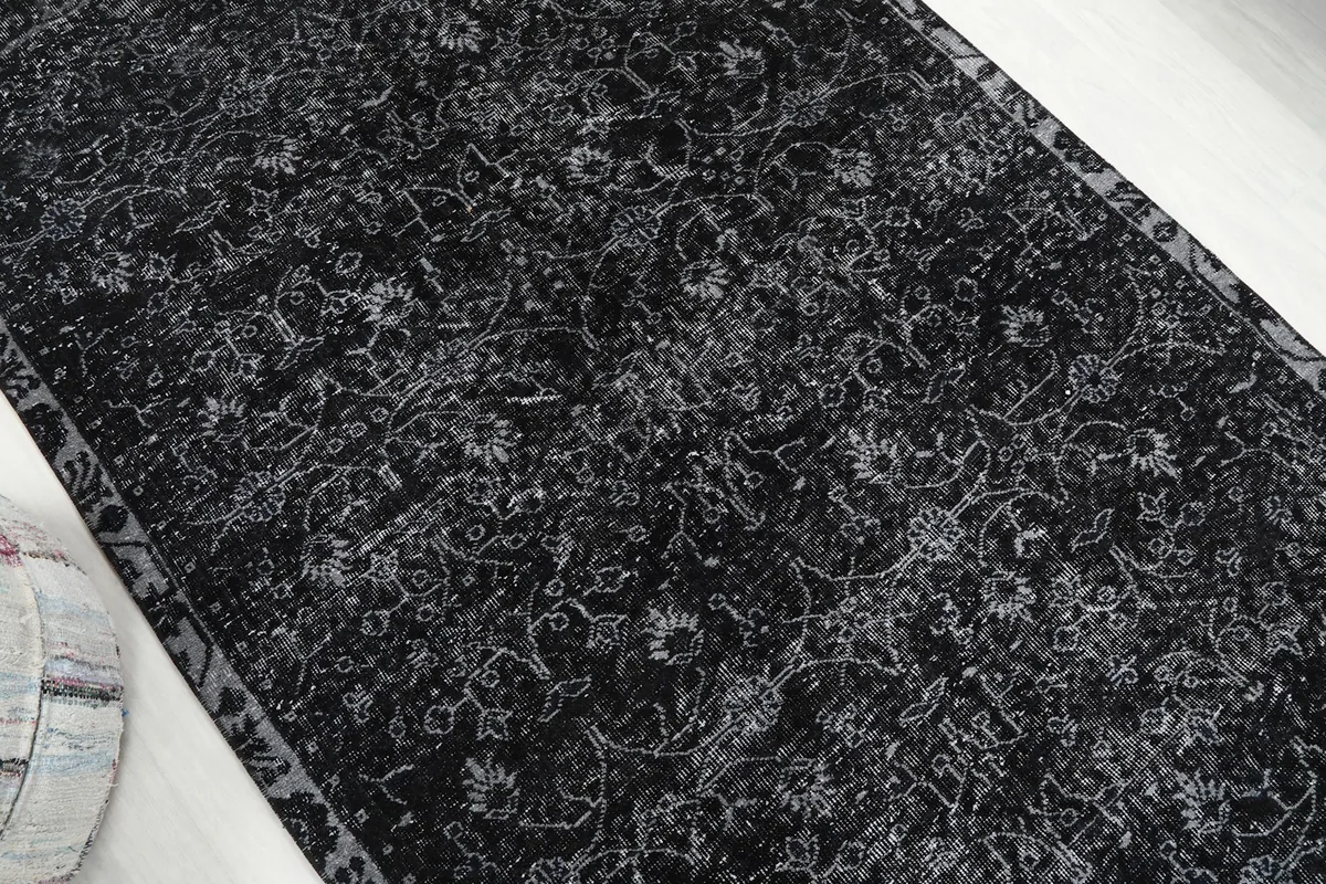 Overhead view showcasing the full length of the vintage black rug with its subtle patterns