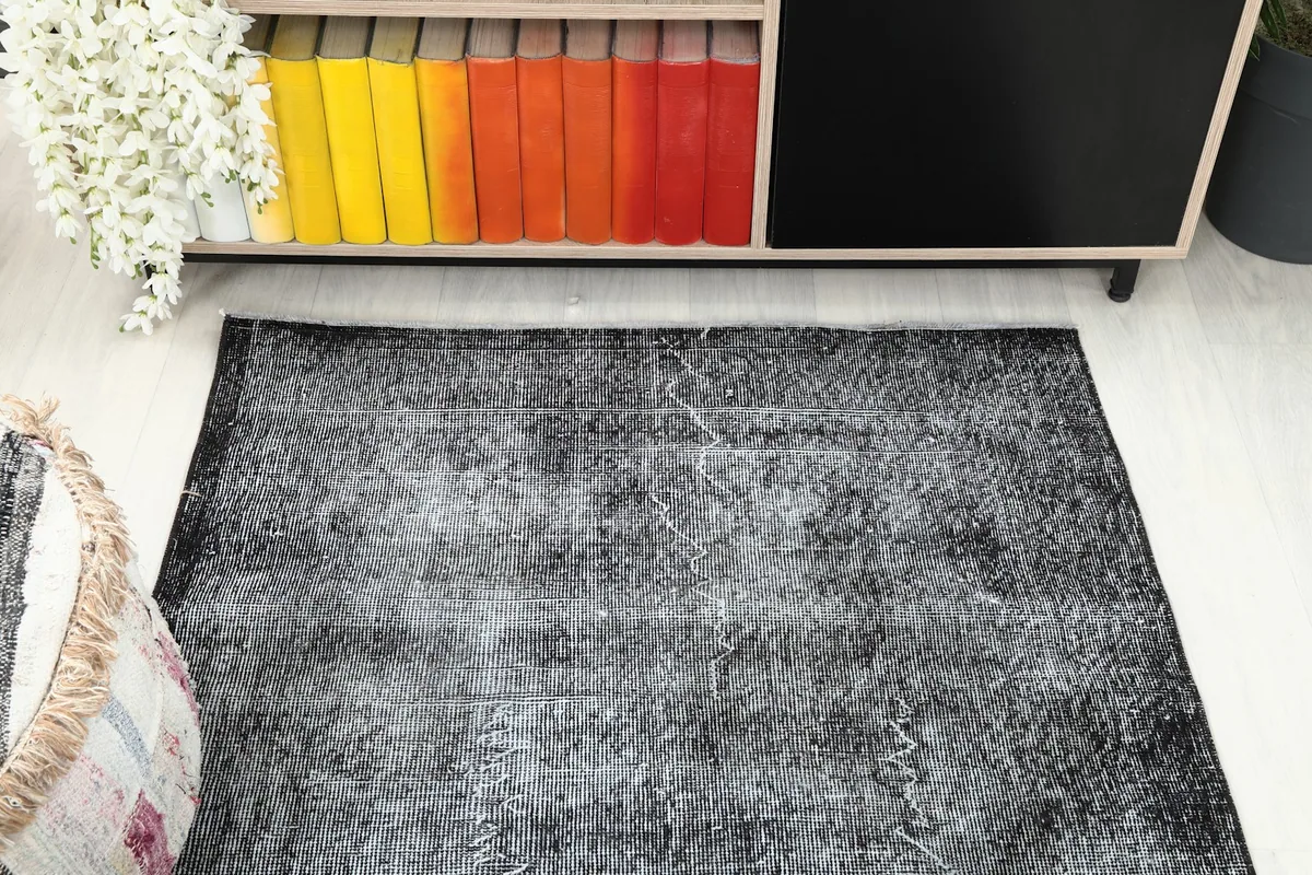 Overhead angled view of the charcoal gray rug, showing its placement near a cabinet with colorful books.