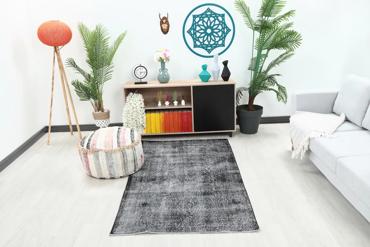 Charcoal gray vintage rug placed in a room setting with a light gray couch and colorful decor.