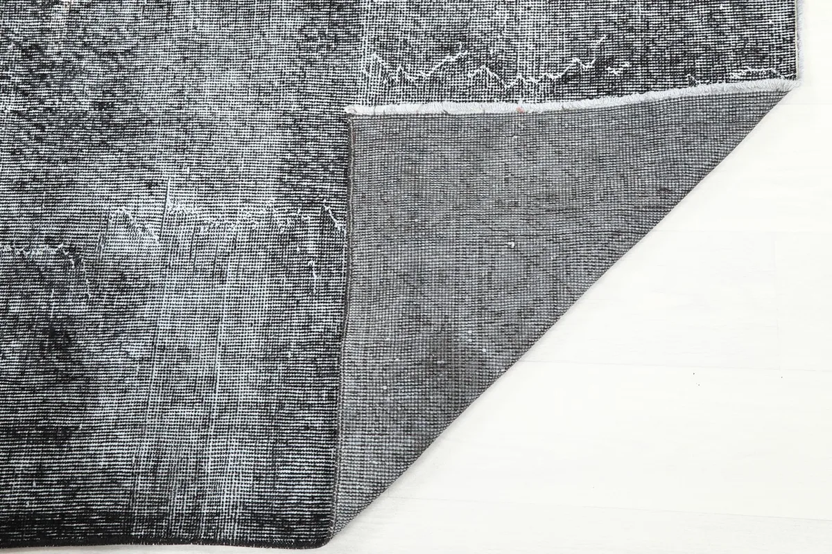 Close-up of the back of the charcoal gray hand-knotted rug, showing the cotton foundation.