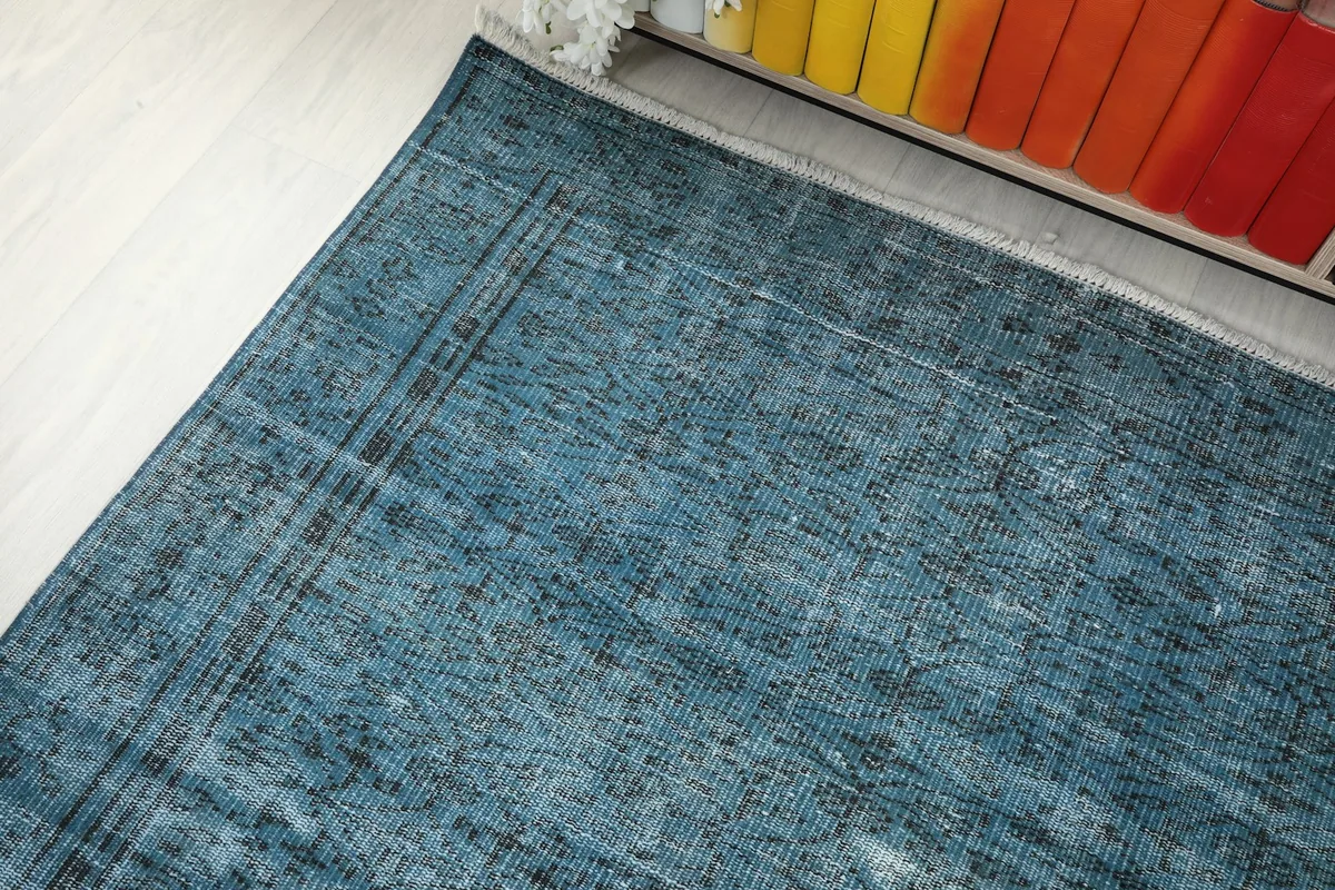 Angle view of the blue distressed rug's edge next to a bookshelf, showing its integration into decor.