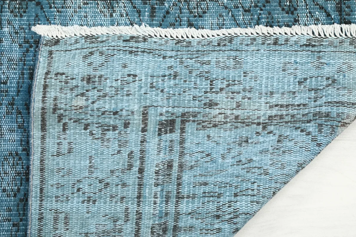 Underside view of the hand-knotted blue vintage rug, showing the cotton foundation and knotting.