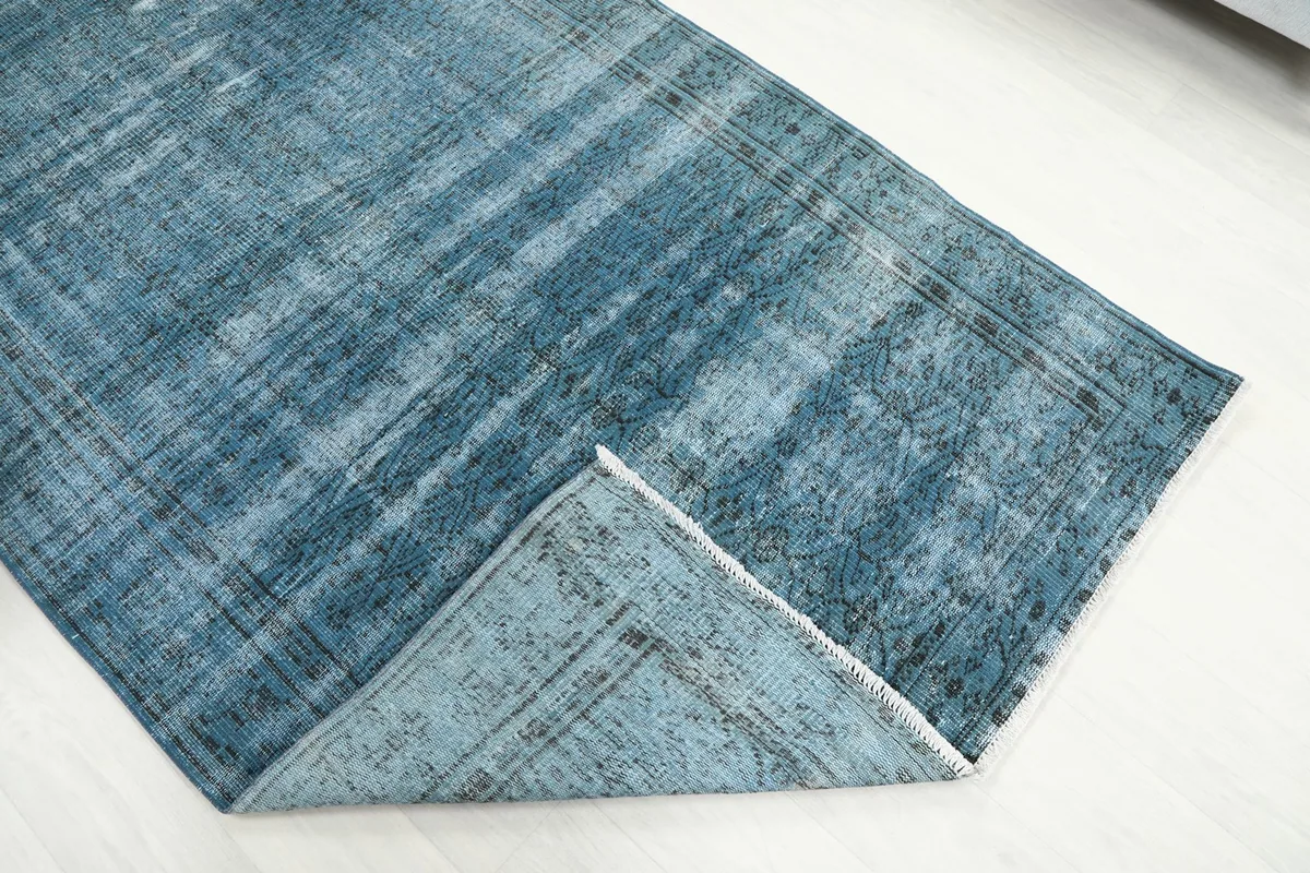 Folded corner of the blue distressed rug, revealing the thickness of the wool pile and cotton foundation.