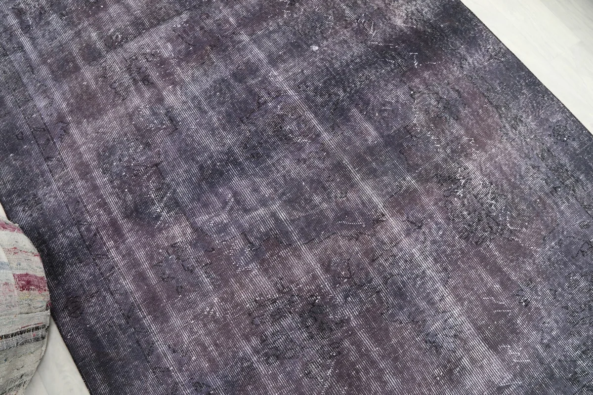 Angled view of the rug's center, revealing the varied color saturation and areas of lighter patina.
