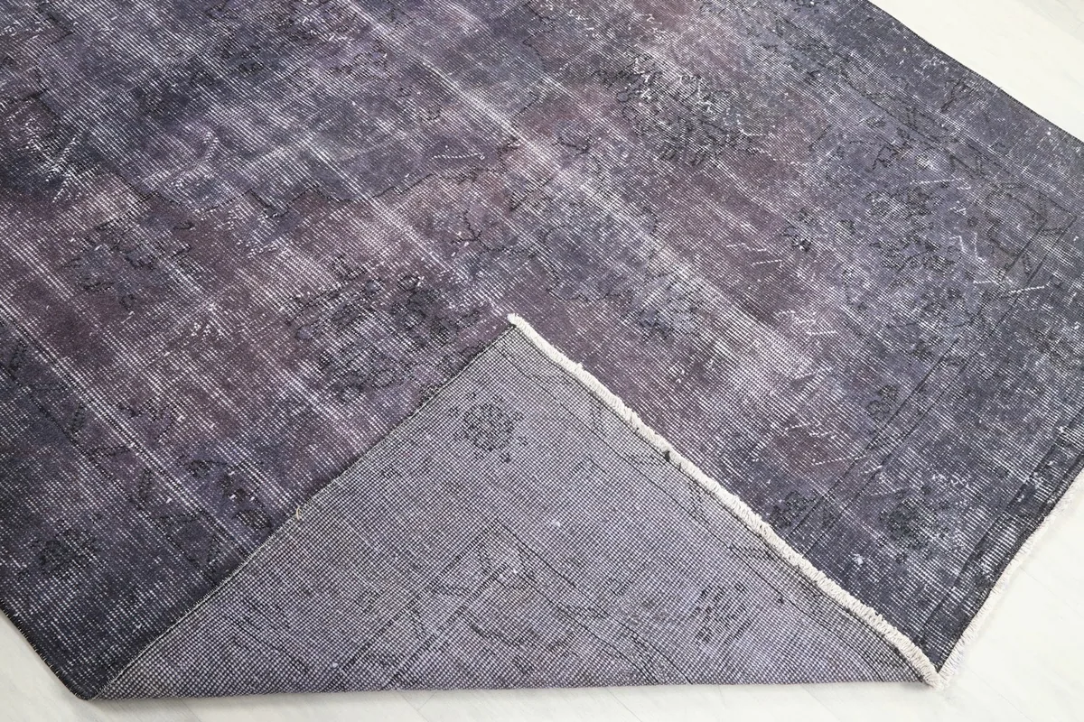The back of the rug partially folded over, revealing the cotton foundation and fine hand-knotting.