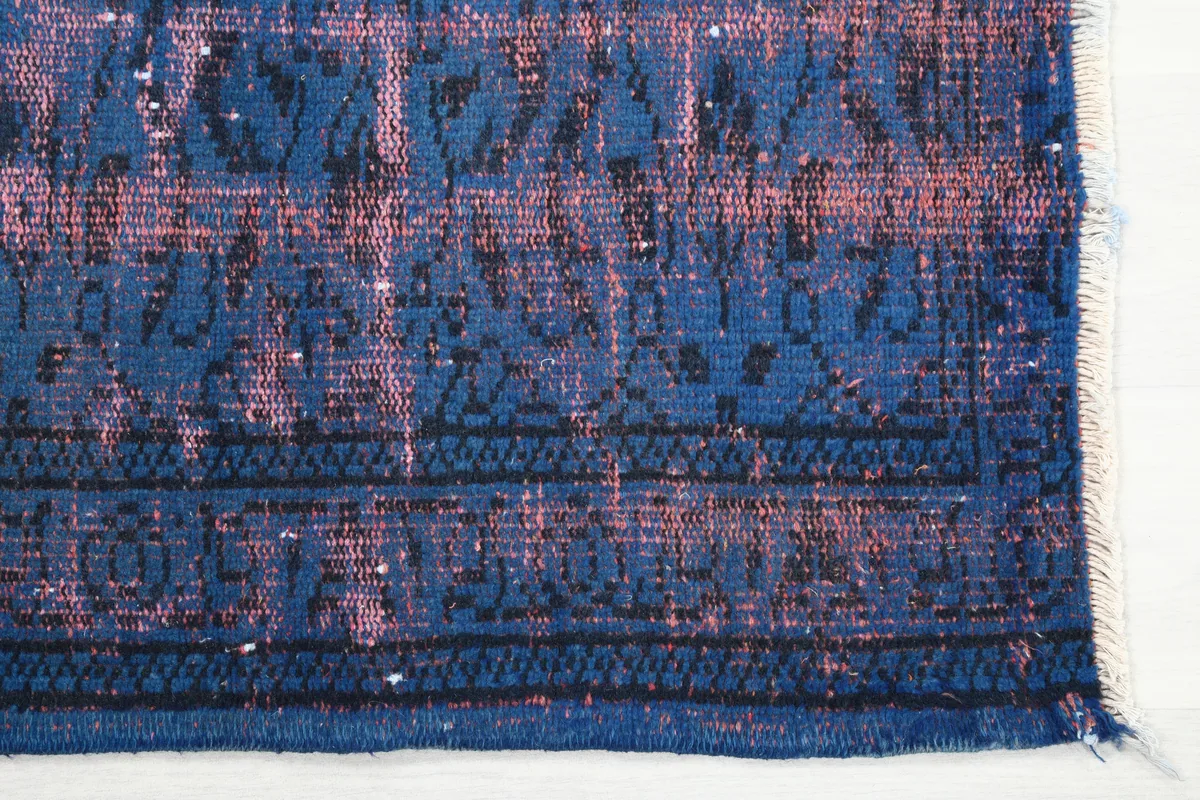 Detail of the border and distressed blue and rose patterns on the rug