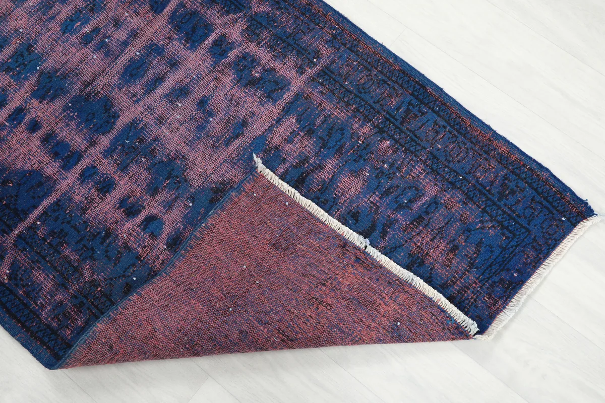 Corner of the rug lifted to show the back and foundation