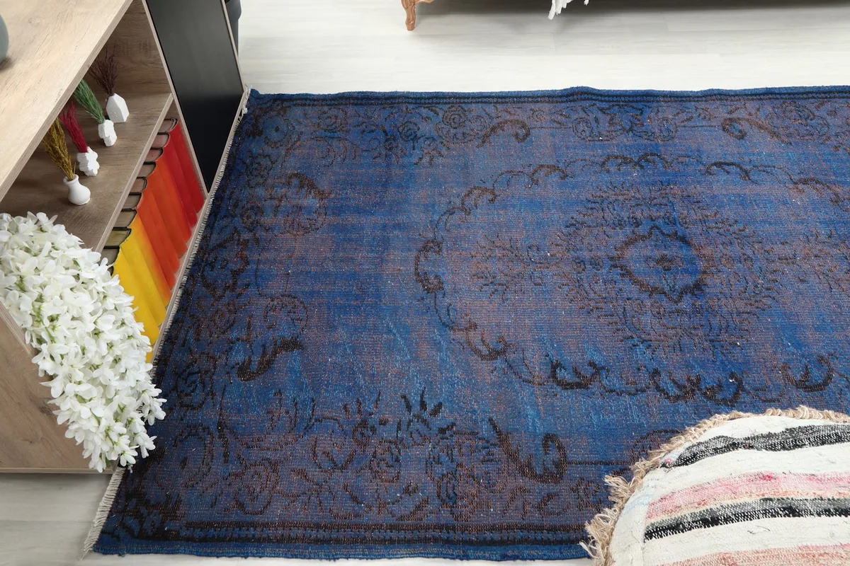 Side angle view of the blue rug, emphasizing its distressed appearance on the floor