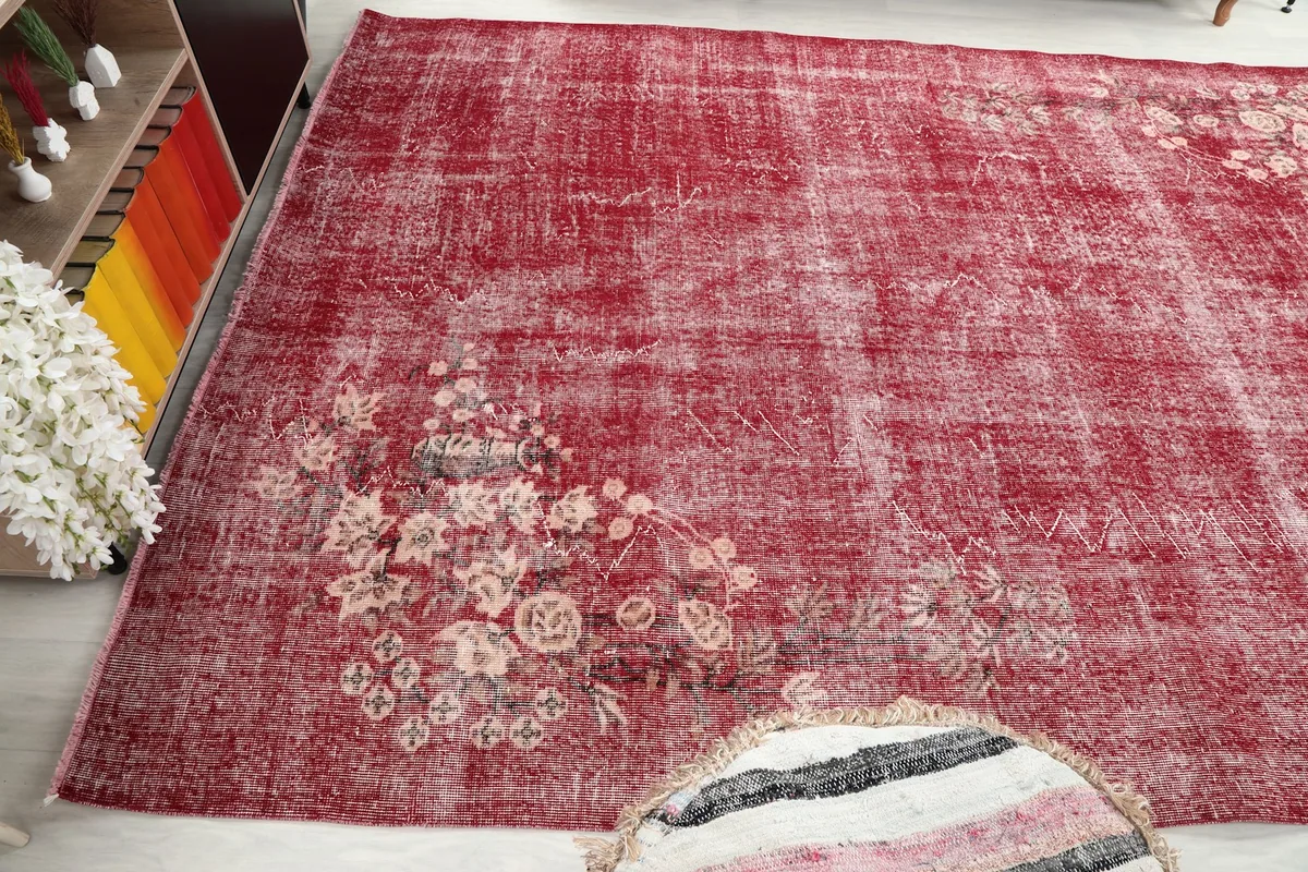 Angled view of the rose rug with a floral pattern in the lower corner