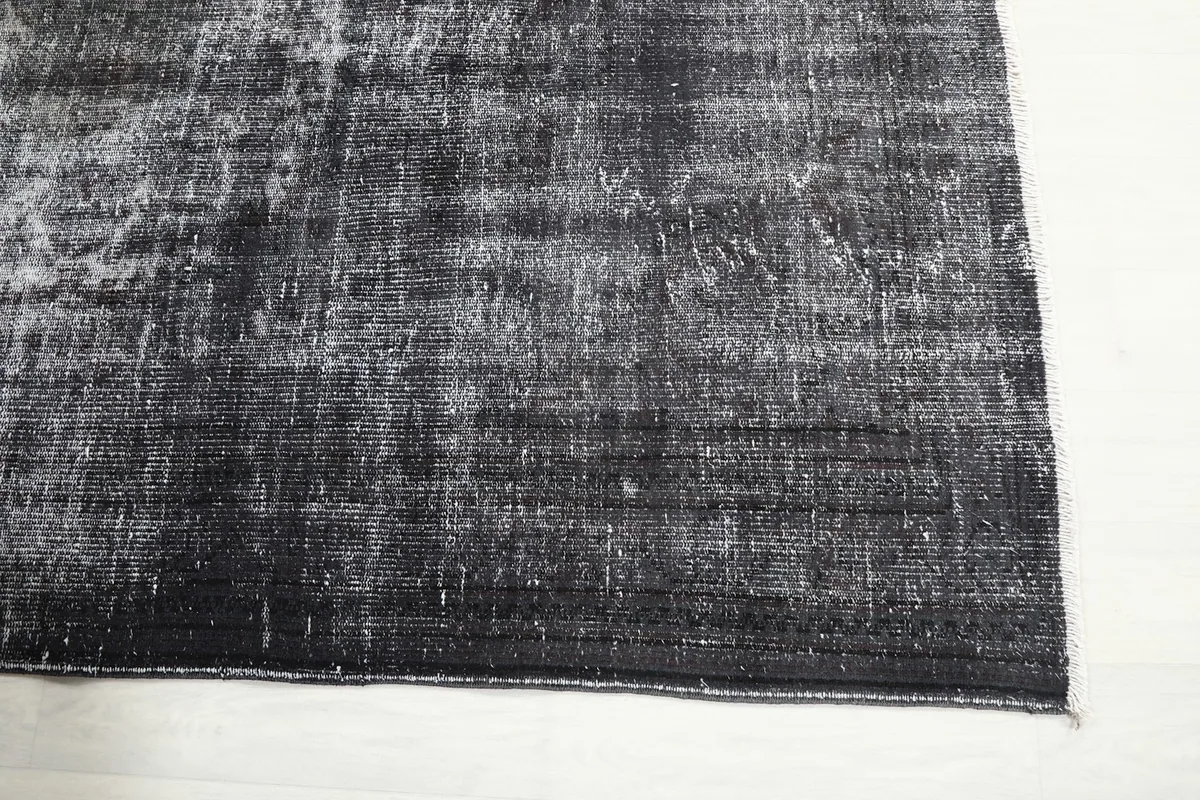 Close-up of the rug's edge, highlighting the charcoal color and low pile