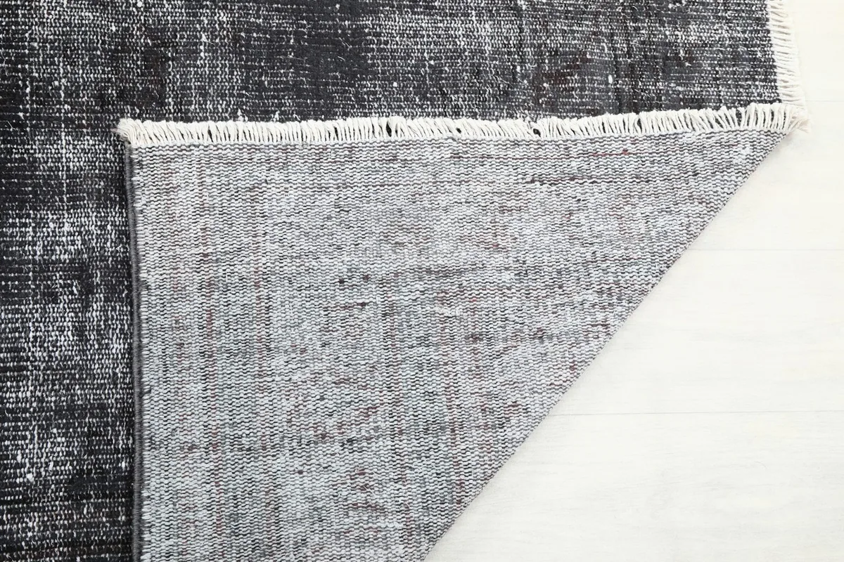 Close-up of the rug's back and fringe, showing the quality of the cotton foundation