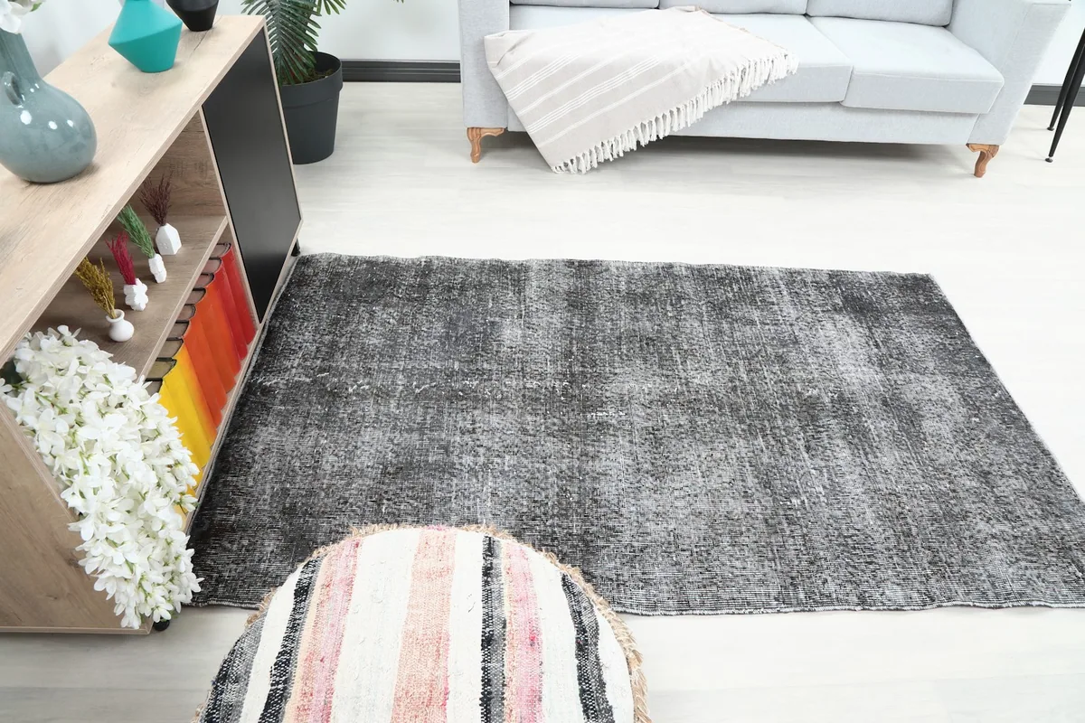The charcoal rug in a room setting, viewed from a different perspective, next to a sofa