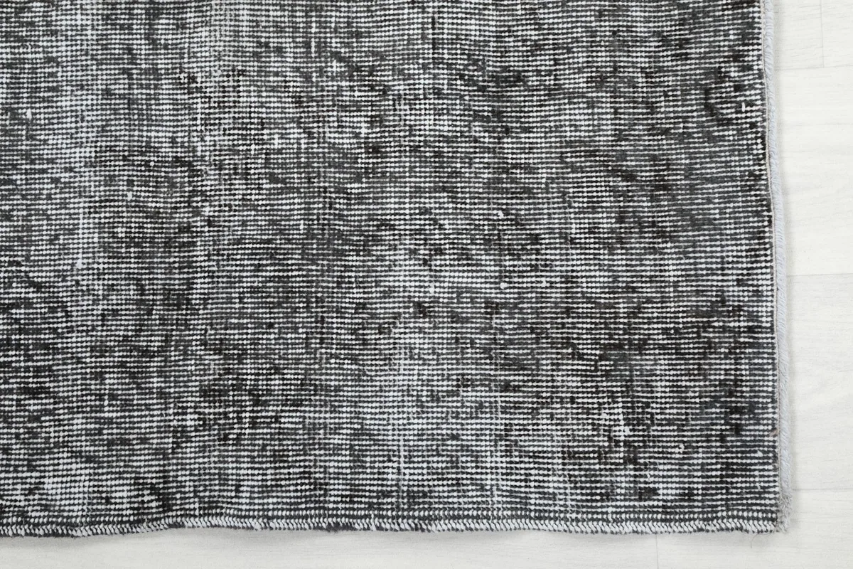 Detailed view of the rug's distressed charcoal and gray wool pile texture
