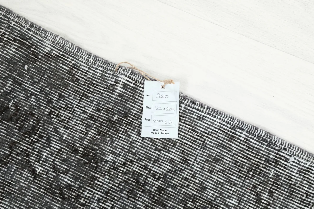 Close-up of the rug's back with a tag, showing the hand-knotted construction