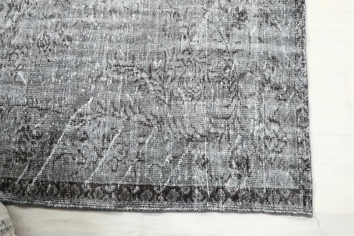 Close-up of the rug's corner, highlighting the charcoal border and faded gray field