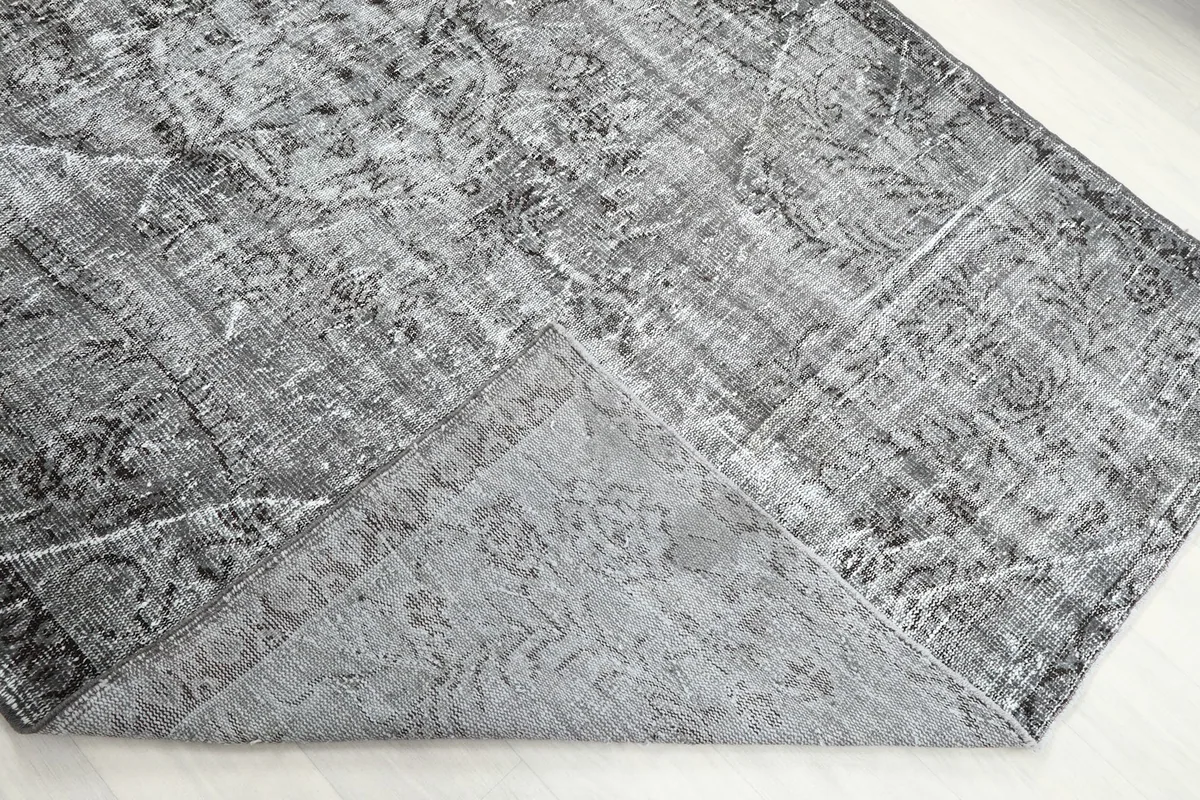Corner of the rug folded back to show the cotton foundation and hand-knotted construction