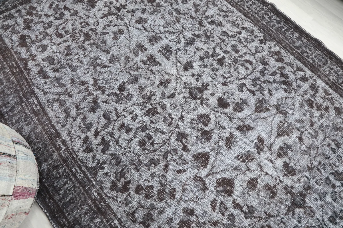 Close-up angled view highlighting the gray and charcoal floral motifs and low pile