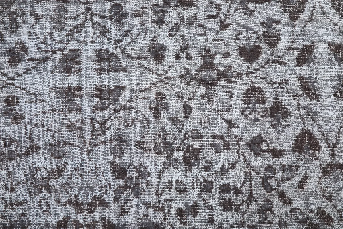 Detailed view of the rug's central floral and geometric patterns in charcoal and gray