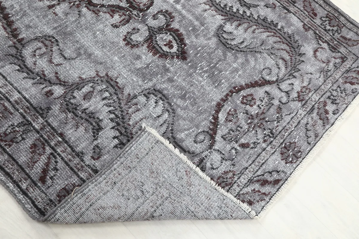 Corner of the rug folded back, revealing the wool pile and cotton foundation
