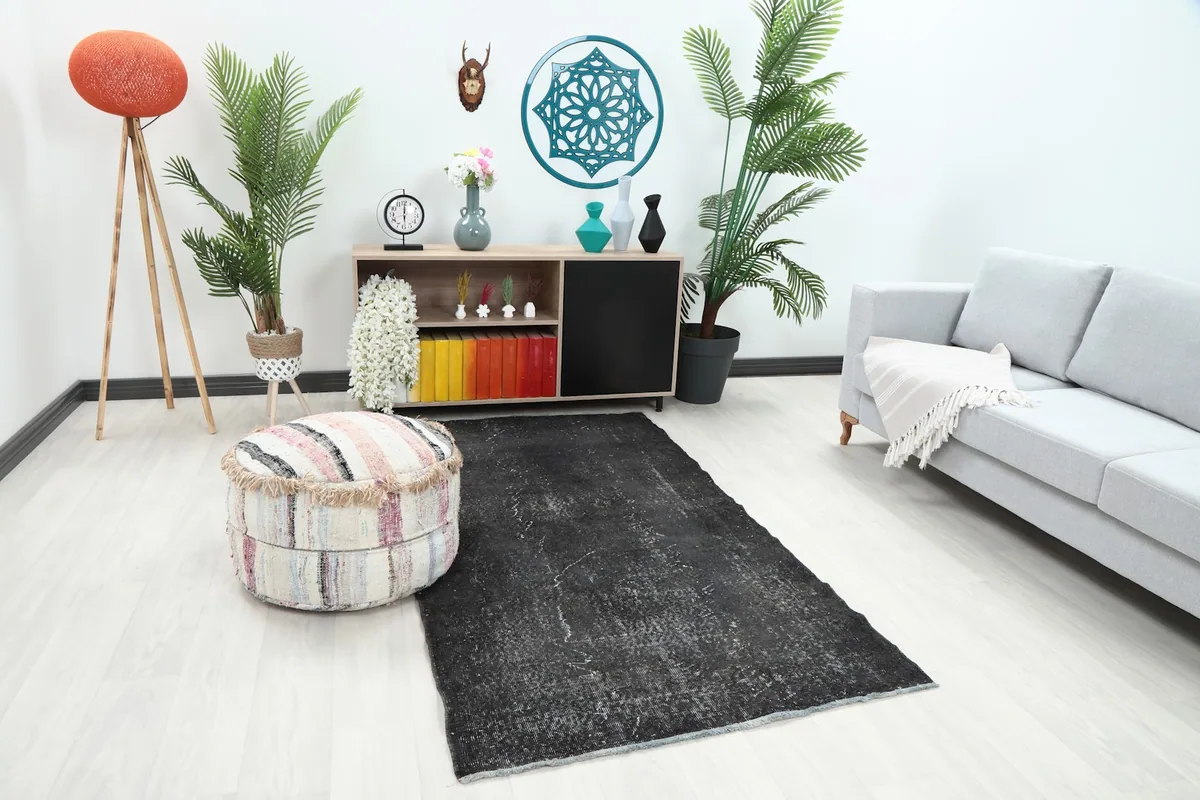 Angle view of the charcoal area rug in a room with a sofa and decorative plants.