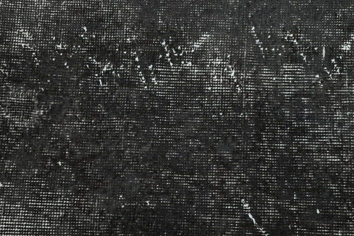 Overhead detail of the low wool pile, revealing the hand-knotted construction and distressed finish.