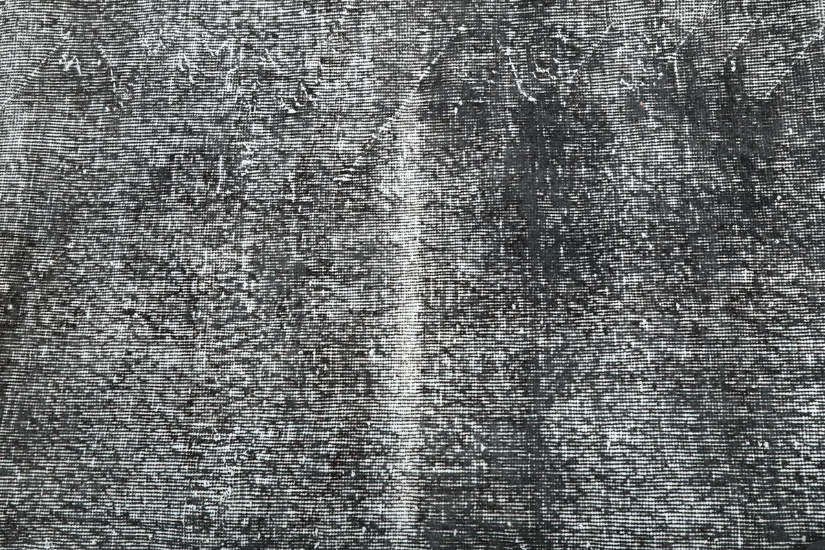Texture detail of the hand-knotted wool pile with varying shades of charcoal