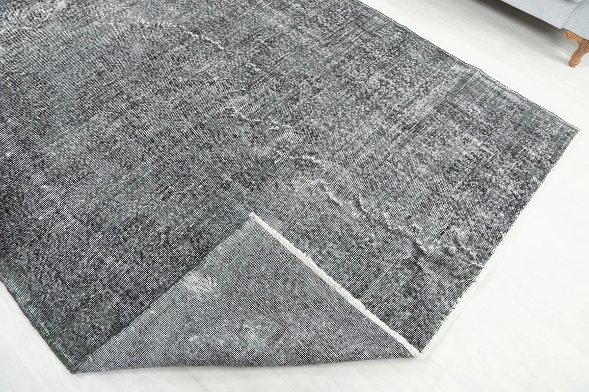 Corner of the rug folded back, revealing the wool pile on cotton foundation