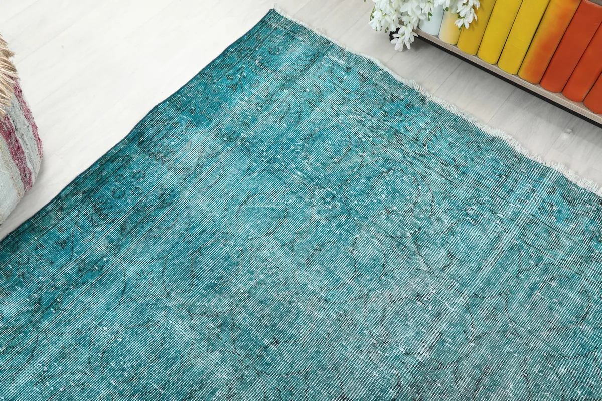 Corner view of the blue rug in the room, showing its placement near a decorative stool.