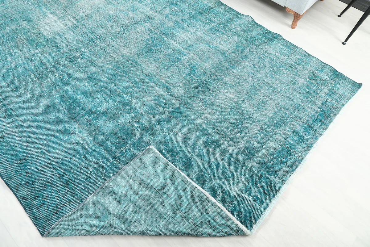 Corner of the rug folded back to show the reverse side and the hand-knotted foundation.