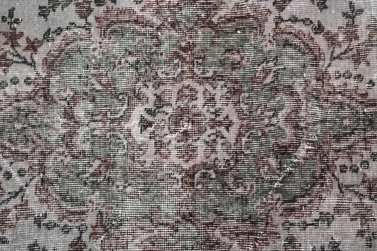 Intricate detail of the rug's central design, showing wear and color variations
