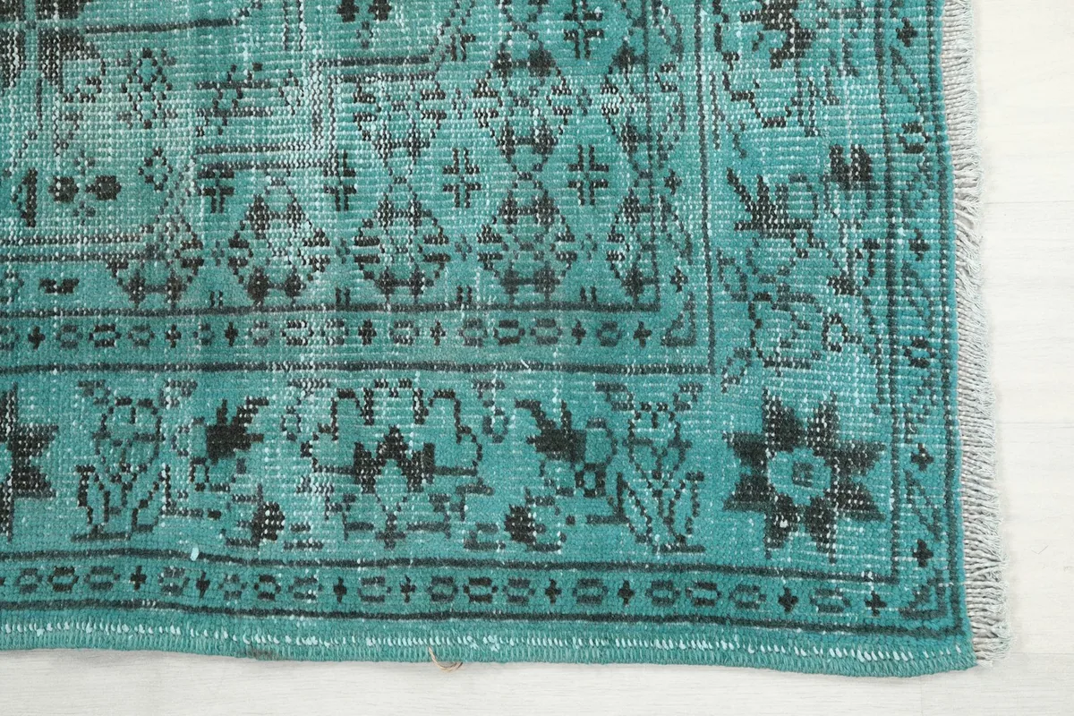 Detail of the rug's short fringe and the black border pattern against the blue field