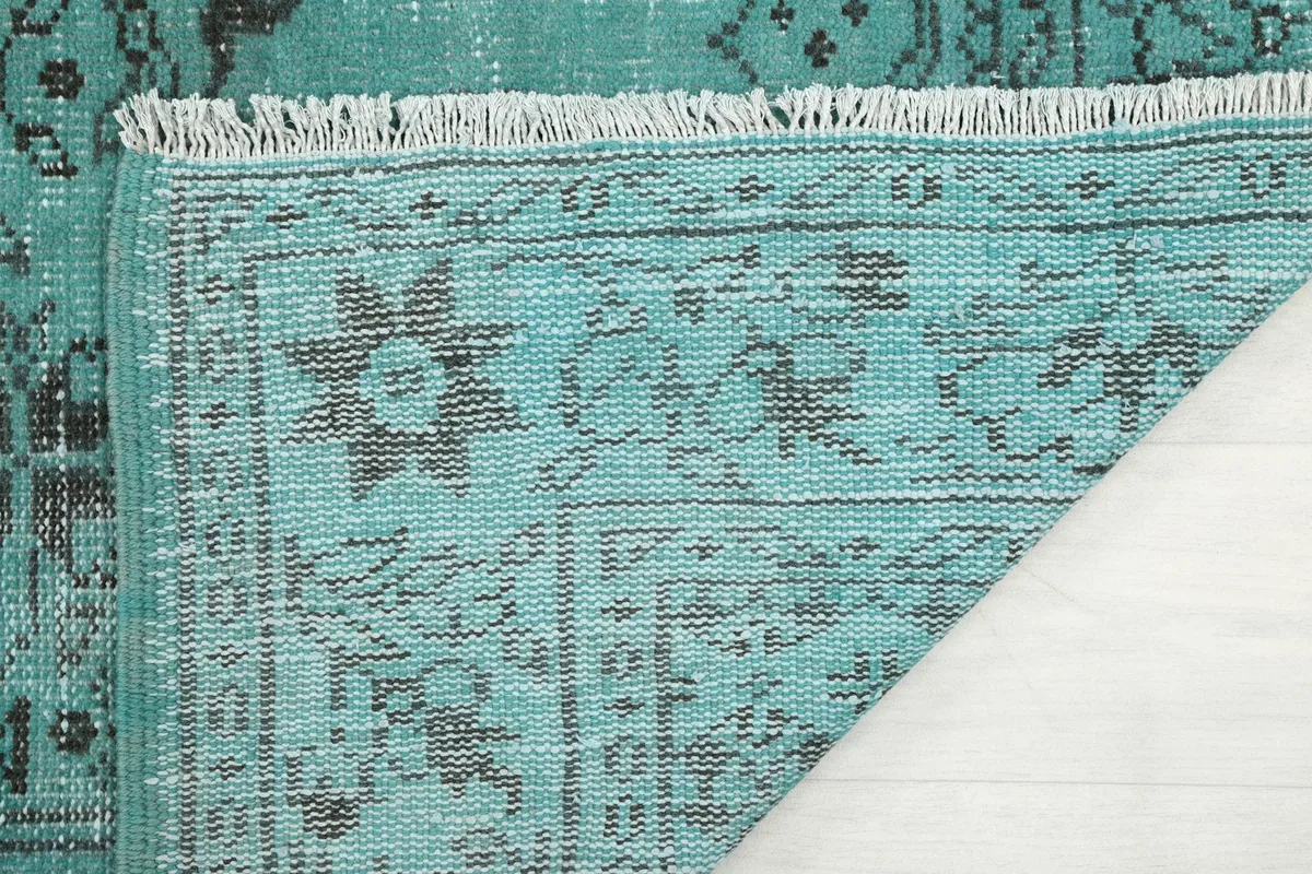 Underside of the rug showing the hand-knotted cotton foundation and fringe