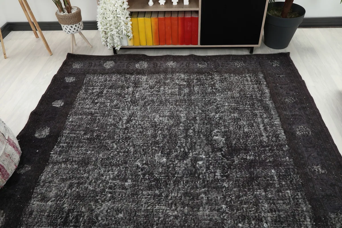 Overhead view of the rug in a room, showing its geometric border and central field.