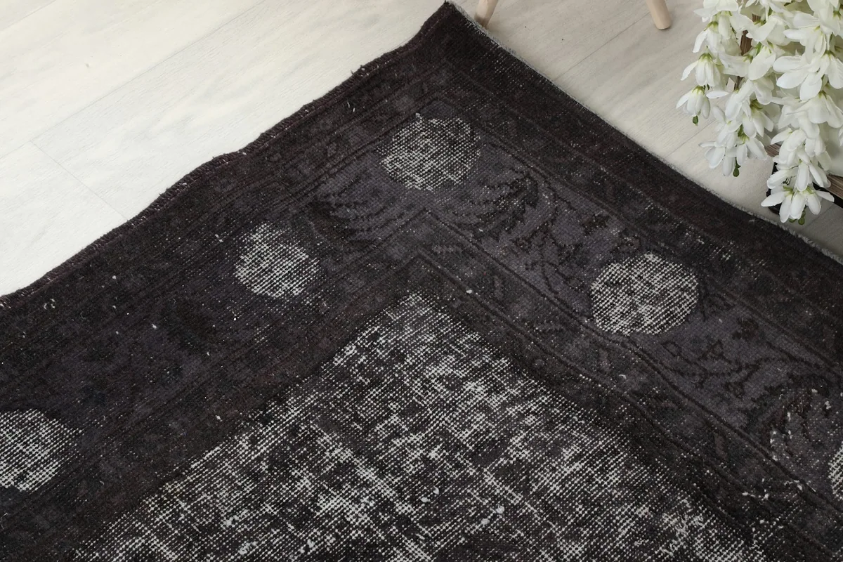 Detail of the rug's border pattern and corner design in charcoal.