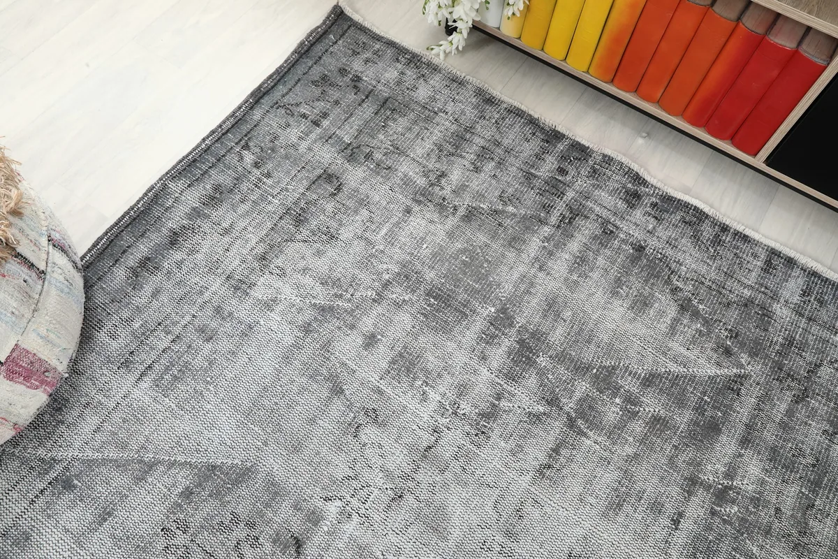 Overhead angle of the gray rug, highlighting its distressed appearance and faint patterns
