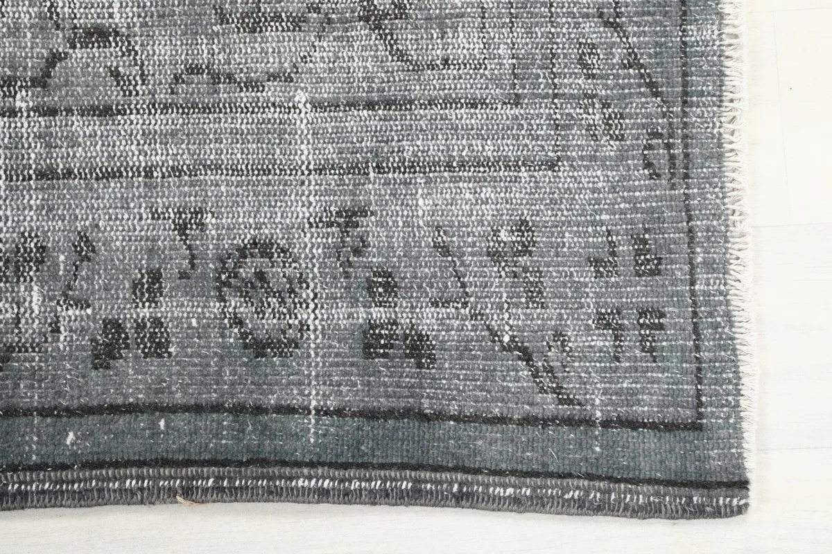 Detail of the rug's charcoal border and faint floral patterns along the edge