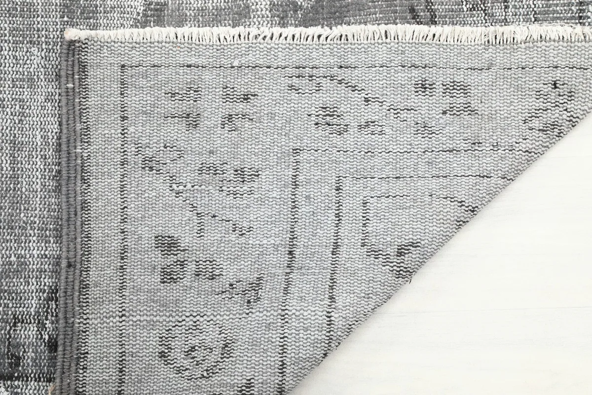 Close-up of the rug's reverse side, showing the hand-knotted cotton foundation and wool knots