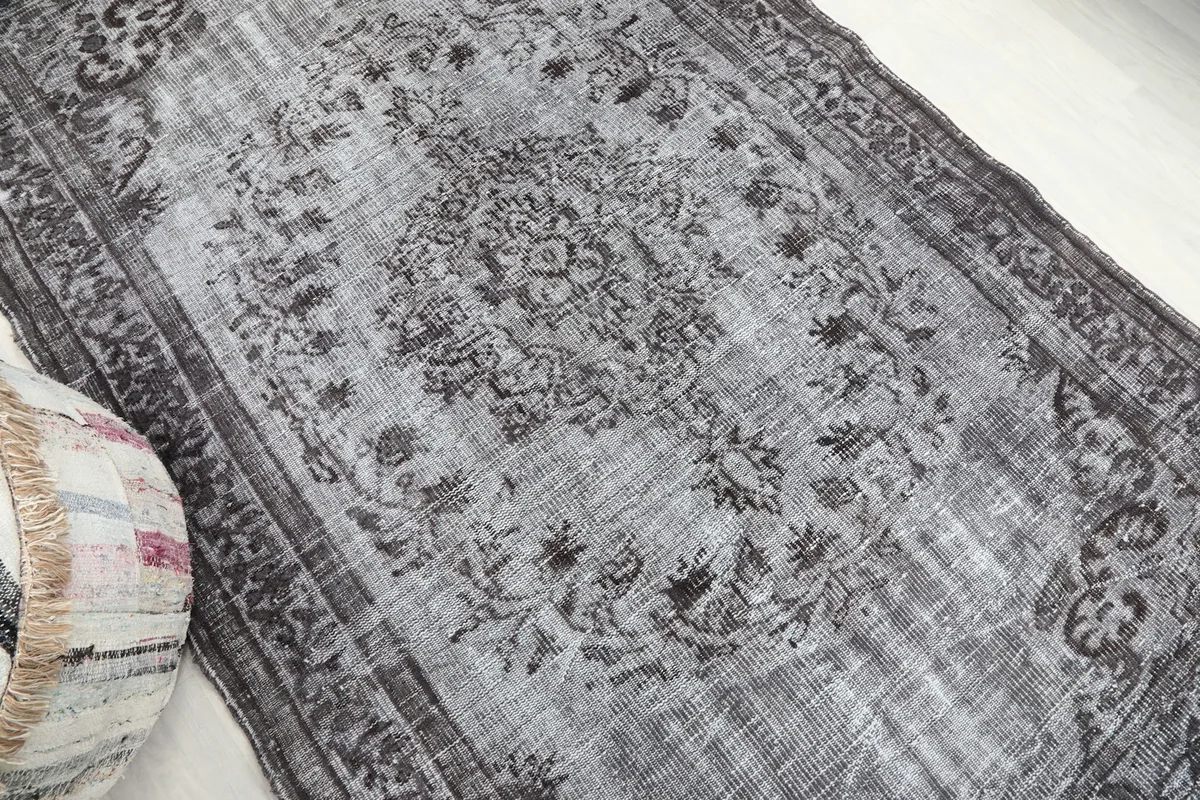 Overhead angle showing the gray field and darker charcoal patterns of the hand-knotted rug.