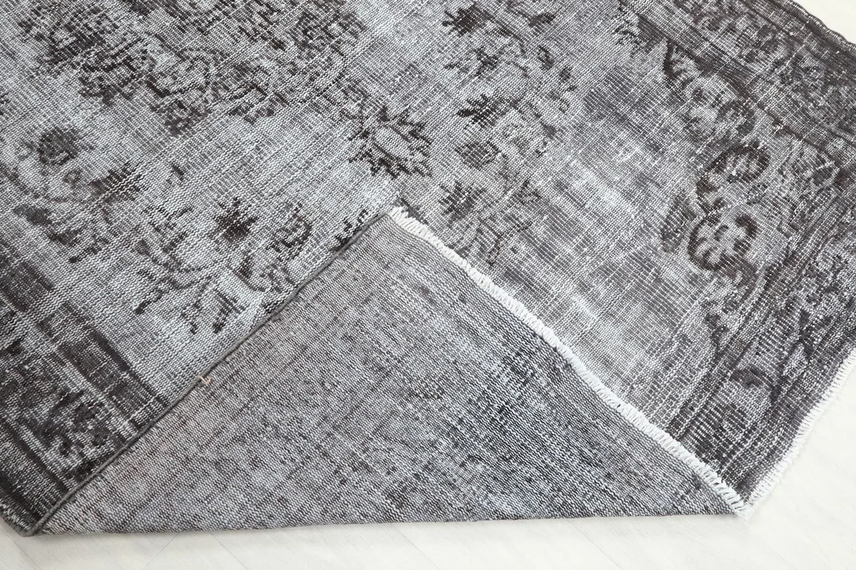 Folded corner of the rug revealing the hand-knotted wool pile and cotton foundation from the back.